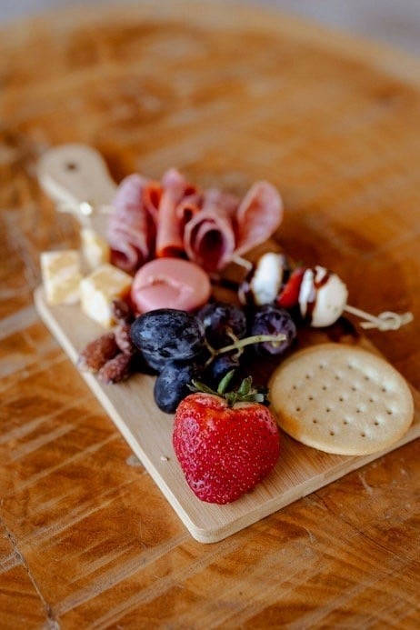 Charcuterie board with cured meats, berries, cheese, and crackers on wooden surface